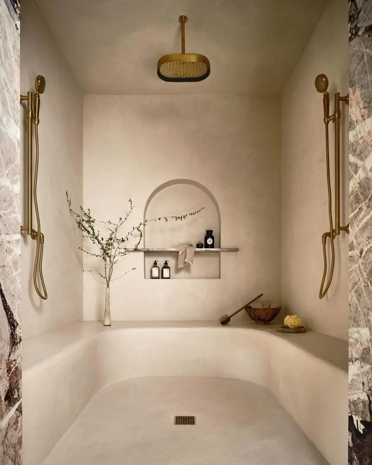 A seamless Tadelakt bathroom surface with an arched niche and brass fittings